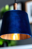 Modern navy blue velvet lampshade with warm glowing light inside creates elegant contrast between dark exterior and golden interior illumination.