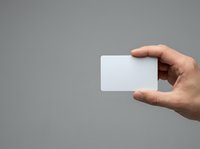 Male hand holding blank white card against neutral gray background for business branding, corporate identity, and marketing presentations.