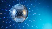 Shiny disco ball with sparkling light rays on blue gradient background for party and nightclub entertainment events.