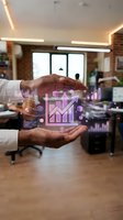 Hands holding glowing neon growth chart icon in modern office with brick walls, representing business analytics, financial success, data visualization, and corporate strategy development.