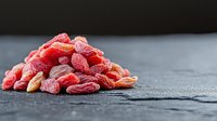 Dried goji berries superfood pile on dark slate surface for healthy nutrition and wellness lifestyle cooking ingredients.