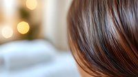 Close up view of shiny brown hair with soft bokeh lights in background creating romantic atmosphere. Natural hairstyling and beauty concept.