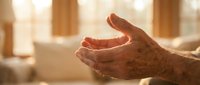 Elderly hands cupped in prayer or meditation gesture with warm sunlight streaming through window creating peaceful spiritual moment for wellness concepts.