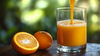 Fresh orange juice being poured into glass with sliced oranges on wooden table outdoors. Healthy breakfast drink concept for morning nutrition.