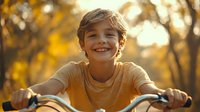 Young boy with bright smile riding bicycle in autumn park during golden hour sunset, warm lighting creates magical childhood moment against blurred fall foliage background.