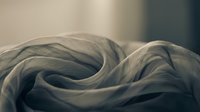 Soft, delicate fabric folds create flowing waves of neutral tones, perfect for textile, fashion, and design backgrounds.