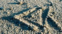 Close-up of love word written in sandy beach surface with natural texture and shadows creating romantic seaside message for vacation memories.