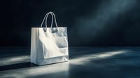 White paper shopping bag with handles on dark blue surface with dramatic lighting for retail and commercial use.