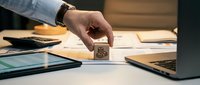 Business professional stamping document with rubber stamp at office desk with laptop and paperwork for approval workflow and administrative tasks.