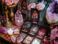 Mystical altar with tarot cards, rose quartz crystals, pink roses, and glowing candles. Vintage brass candlesticks and amethyst geode create magical fortune telling atmosphere.