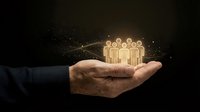 Businessman hand holding glowing people icon with network connections on dark background, representing team building, leadership, community management, and human resources solutions.