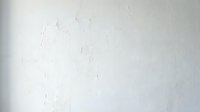 White textured wall surface with subtle cracks and weathered plaster finish for interior design backgrounds and architectural projects.