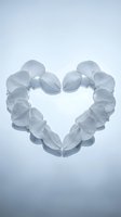 Delicate white flower petals arranged in heart shape on soft blue gradient background for romantic wedding and love concepts.