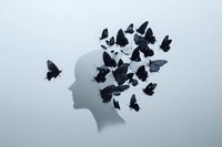 Black butterflies emerging from a human head silhouette on gray background, symbolizing mental freedom, thoughts, and transformation.