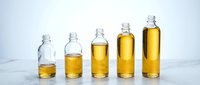 Bottles with golden liquid increasing in volume from left to right, representing growth, progress, and business expansion on white surface.