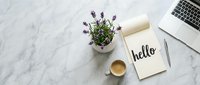 Flat lay workspace on marble desk with lavender plant, coffee cup, notebook with hello lettering, pen and laptop, top view.