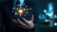 Businessman hand holding glowing virtual network of connected user icons with central bright light, representing digital networking and leadership.