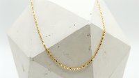 Gold beaded necklace on concrete cube display stand, minimalist jewelry styling for fashion and accessories marketing.