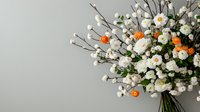 Elegant floral arrangement featuring white ranunculus and orange poppies with delicate baby's breath against neutral gray background, creating modern minimalist composition.