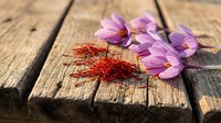 Dried saffron threads and fresh crocus flowers on rustic wooden surface, showcasing the world's most precious spice for culinary and herbal concepts.