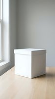White cardboard gift box with lid on wooden table near window in minimalist room interior for packaging and storage solutions.