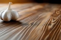 Fresh white garlic bulb on rustic wooden table surface with natural grain texture for cooking and culinary applications.