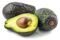 Fresh ripe hass avocados, whole and cut in half showing creamy flesh and pit, isolated on white background for food photography and packaging design.