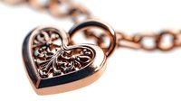 Rose gold heart pendant with ornate filigree pattern on chain necklace against white background, isolated jewelry macro photography for luxury accessories.