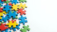 Colorful jigsaw puzzle pieces scattered on white background with copy space for teamwork, problem solving, and business strategy concepts.