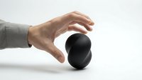 Hand reaching toward black sphere on white background demonstrating protection, control or energy concept for business presentations and wellness designs.