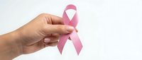Hand holding pink ribbon symbol for breast cancer awareness campaign and women health support on white background.