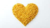 Golden heart shape made from granulated powder or crumbled texture isolated on white background, suitable for love, charity and wellness design projects.