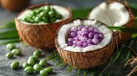 Colorful candy dragees in coconut shell bowls, green and purple sugar-coated almonds on tropical palm leaves for party dessert table.