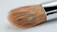 Professional makeup brush with soft brown bristles and silver ferrule on white background for cosmetic application and beauty routines.