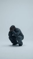 Depressed man crouching with head in hands showing mental health struggle and emotional pain on neutral background for therapy concepts.