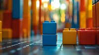 Colorful plastic building blocks arranged on reflective surface with soft bokeh background creating dreamy childhood atmosphere. For educational concepts.