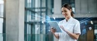Young Asian female healthcare professional using digital tablet with futuristic holographic interface in modern medical facility for telemedicine applications.