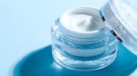Luxurious moisturizing cream in elegant glass jar with open lid revealing smooth white texture for premium skincare and beauty routine applications.