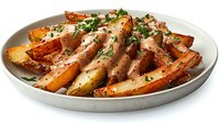 Crispy roasted potato wedges with creamy sauce, fresh herbs and spices served on round white ceramic plate. Restaurant quality appetizer presentation.