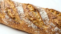 Crusty artisan baguette with flour dusting on white background, ready for bakery, food, and culinary design projects.