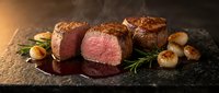 Gourmet beef tenderloin steaks with perfect medium-rare doneness, seared scallops and fresh rosemary on dark slate, ideal for upscale dining menus.