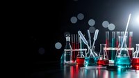 Laboratory glassware with colorful chemical solutions on dark background with dramatic lighting for scientific research and experimentation concepts.