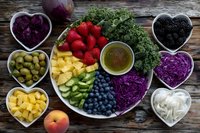 Colorful healthy food platter with fresh fruits, vegetables and superfoods arranged on rustic wooden table for clean eating and nutrition lifestyle.