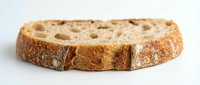 Sliced whole wheat bread with visible air pockets and crispy crust, suitable for bakery, food, and nutrition-related projects.