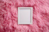 White wooden frame on pink fluffy faux fur background. Minimal feminine flat lay composition with empty photo frame for mockup and design presentation.