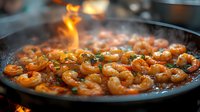 Flaming shrimp sautéed in pan with herbs and spices, cooking in hot oil with dramatic fire flare-up creating spectacular culinary moment. Fresh seafood preparation.