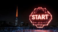 Glowing neon start sign against night city skyline with illuminated skyscrapers and geometric light trails creating futuristic urban landscape.