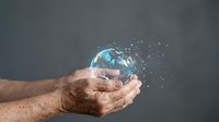 Male hands gently holding glowing Earth globe with sparkling particles, symbolizing environmental protection and global responsibility.
