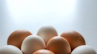 Fresh organic chicken eggs in brown and white colors arranged on clean surface for cooking and baking ingredients in kitchen food preparation.