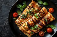 Grilled salmon fillets with caramelized glaze, garnished with fresh basil leaves and cherry tomatoes served on black plate against dark background.